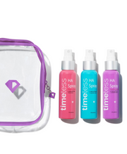 Clear Timeless cosmetic bag with purple trim next to three HA Spray bottles in pink, blue, and purple on a white background.